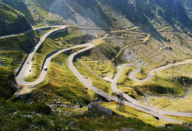 Vedere de sus: drumul Transfăgărășan cu serpentine și mașini pe versanții Munților Făgăraș, lumină de zi